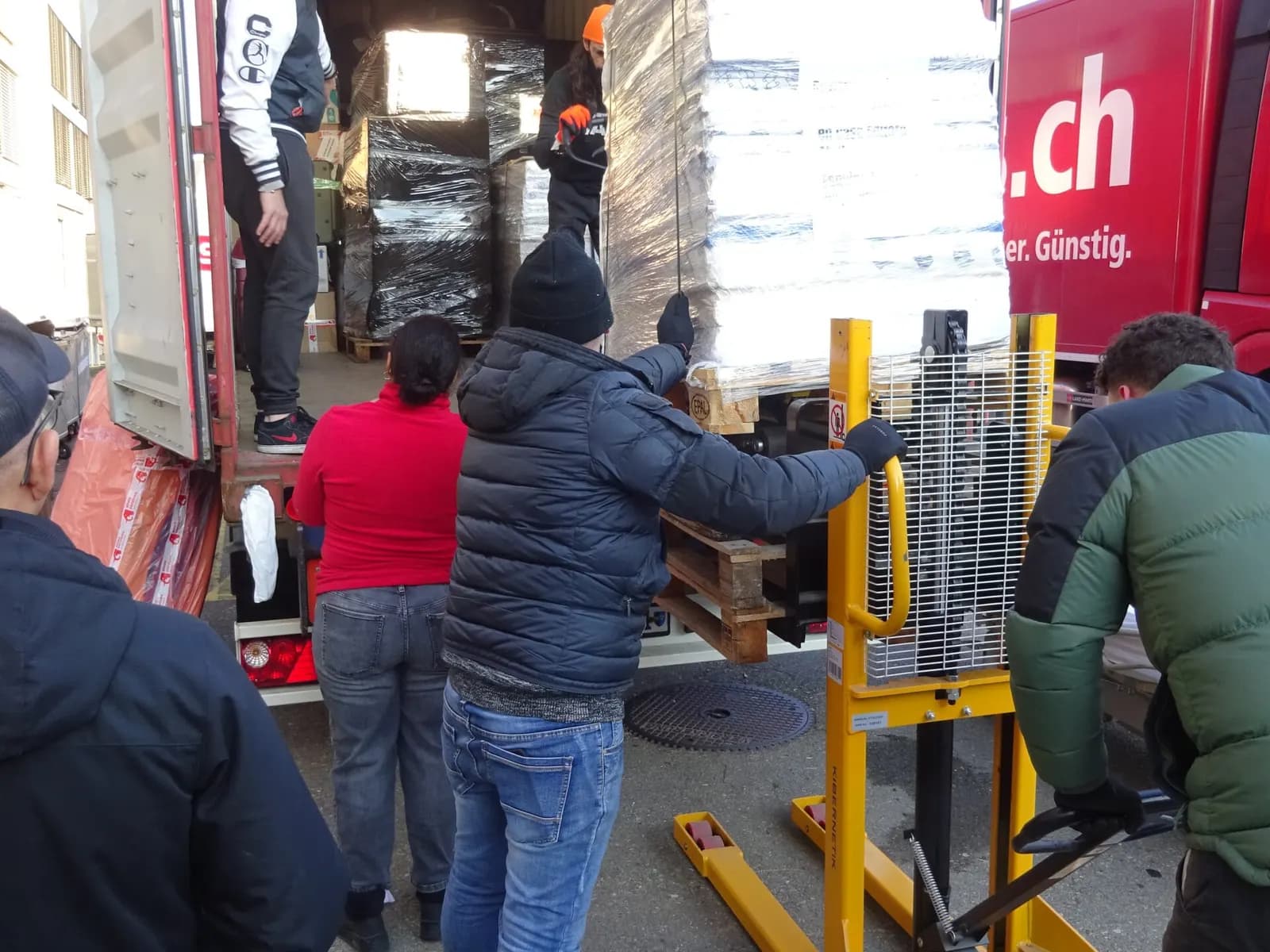 Voluntarios subiendo palés al contenedor